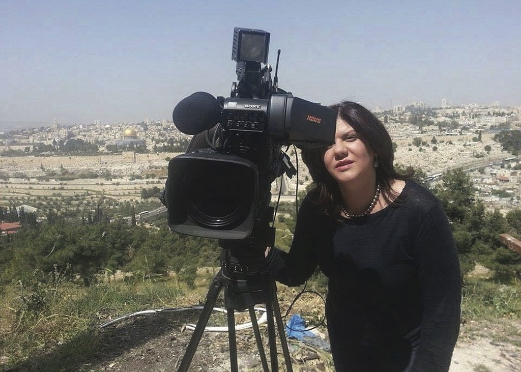 A woman standing next to a news camera