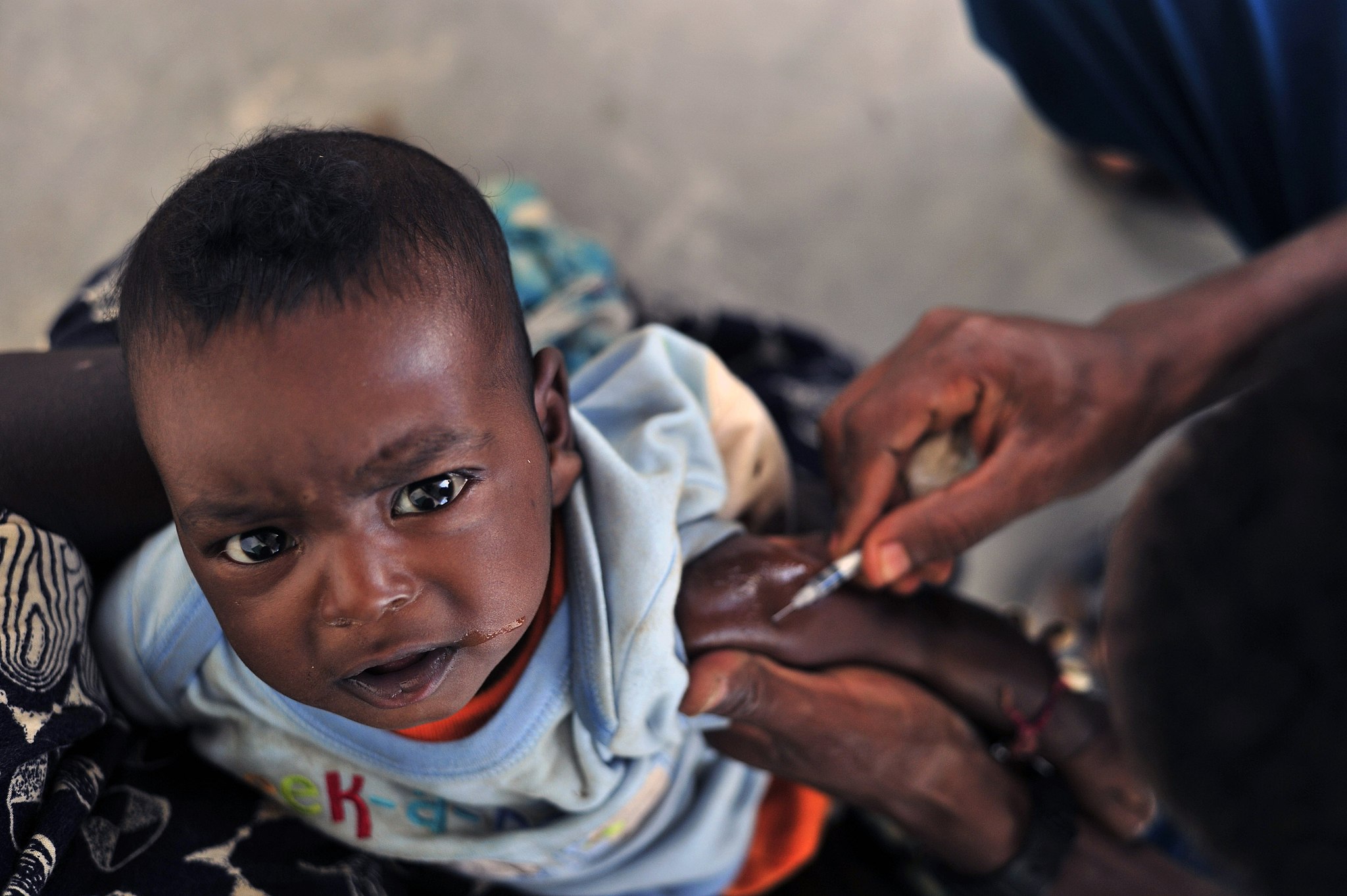 A child crying while receiving a vaccine shot in their arm