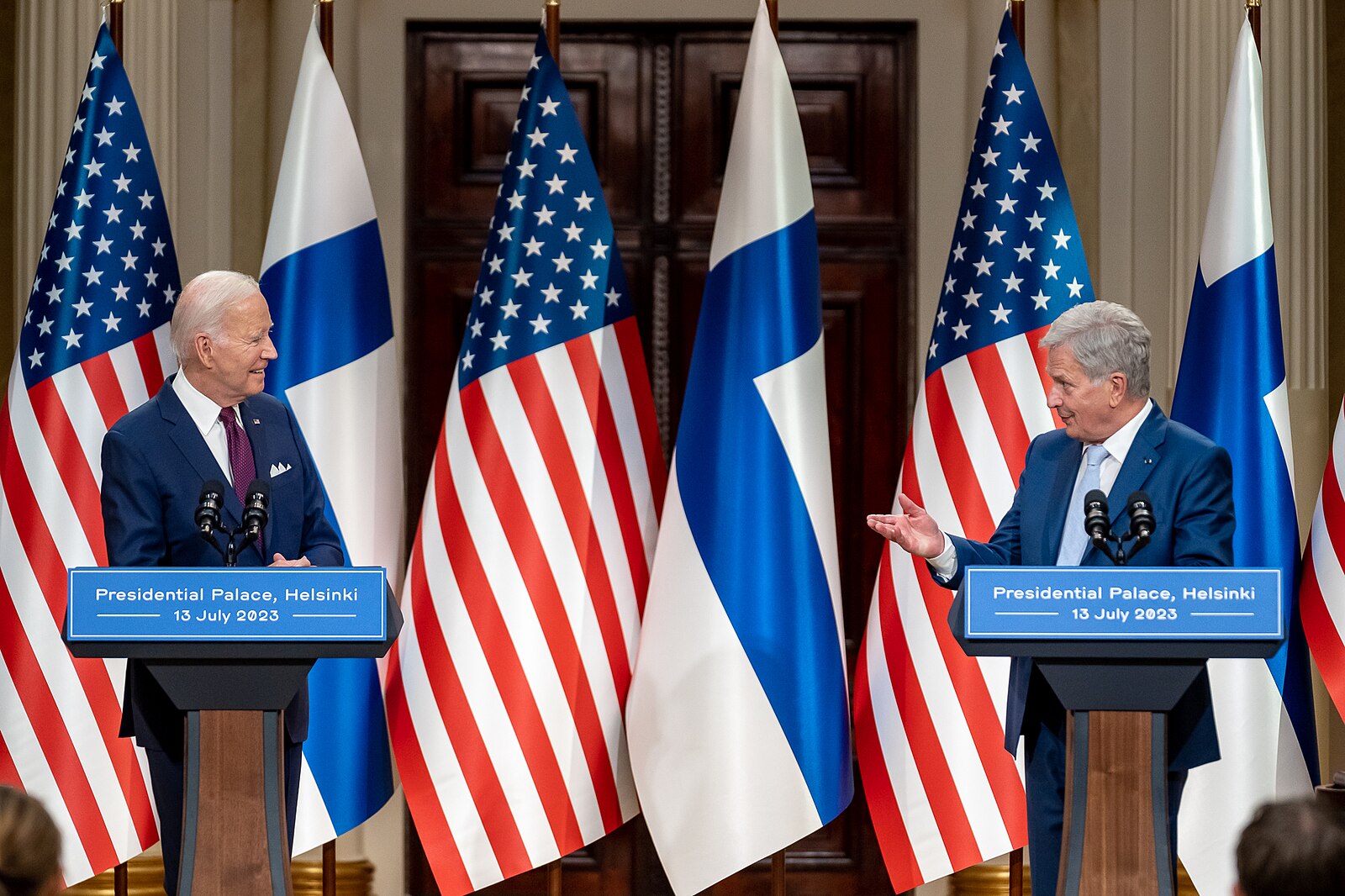 American President Biden and Finnish President Niinisto having a press conference in Helsinki in front of American and Finnish flags.