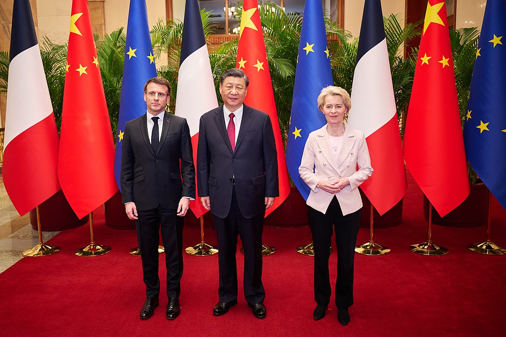 French President Emmanuel Macron standing in front of three flags with Ursula von der Leyen, President of the EU Commission, and Xi Jingping in Beijing in April 2023