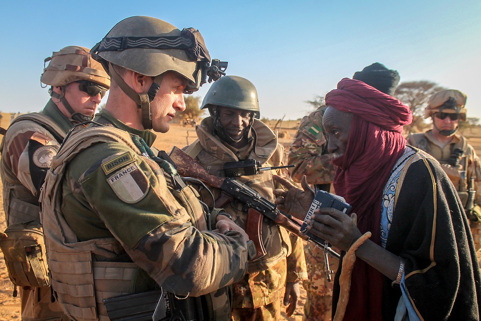 A French soldier talking with a Malian civilian in the desert.
