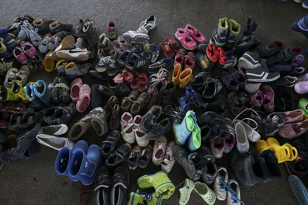 The shoes of migrant children displayed in a pile in Budapest, Hungary in 2015 with a concrete background