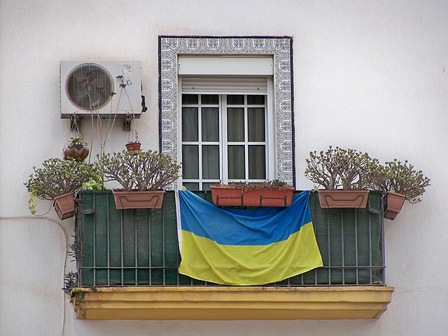 An Ukrainian flag being displayed over a balcony.