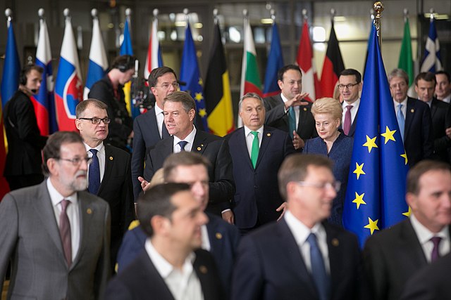 Prime Minister Viktor Orban at a European Council meeting walking among a large group of other European heads of government.