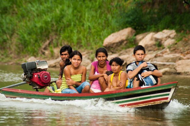 Five people in a small boat on a river. 