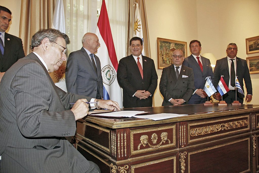 A group of people around a desk signing a World Cup proposal