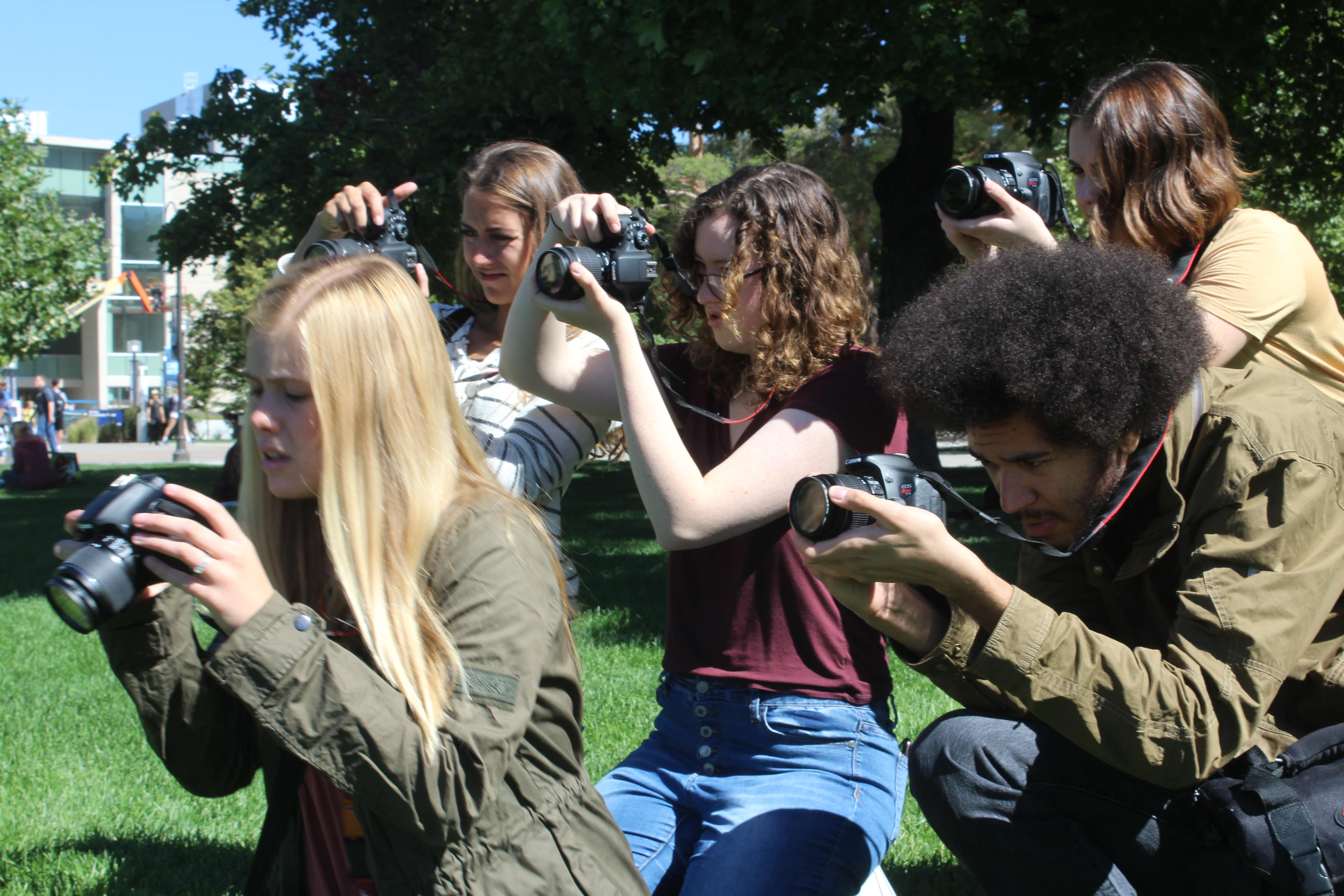 A handful of students holding camera to their face