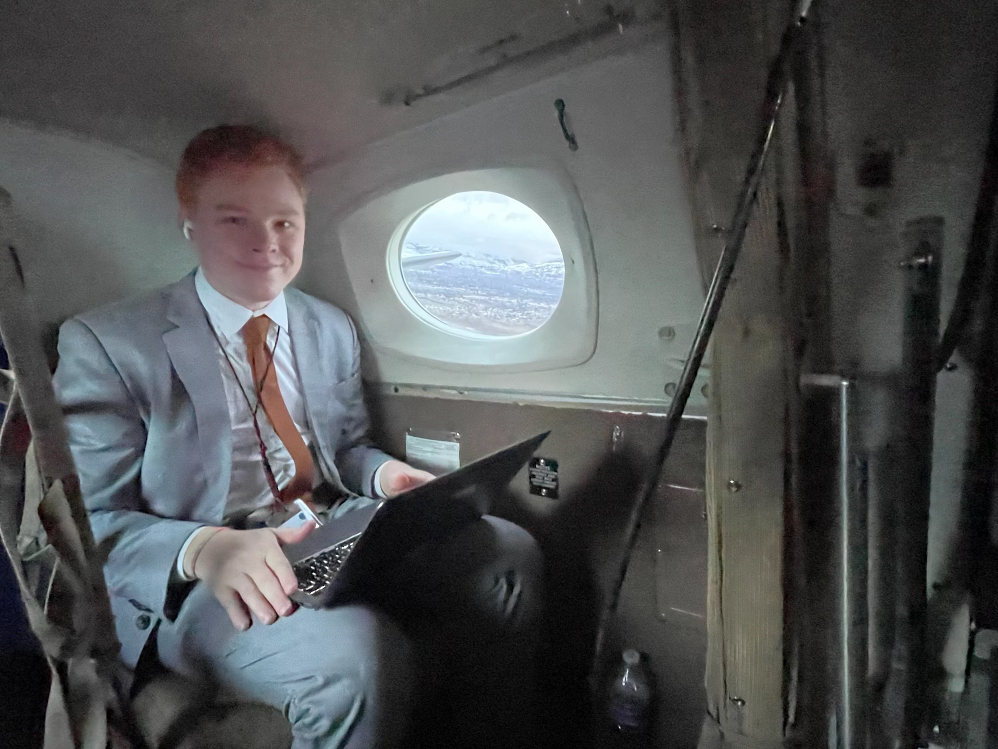 Red haired man working on a computer in an airplane
