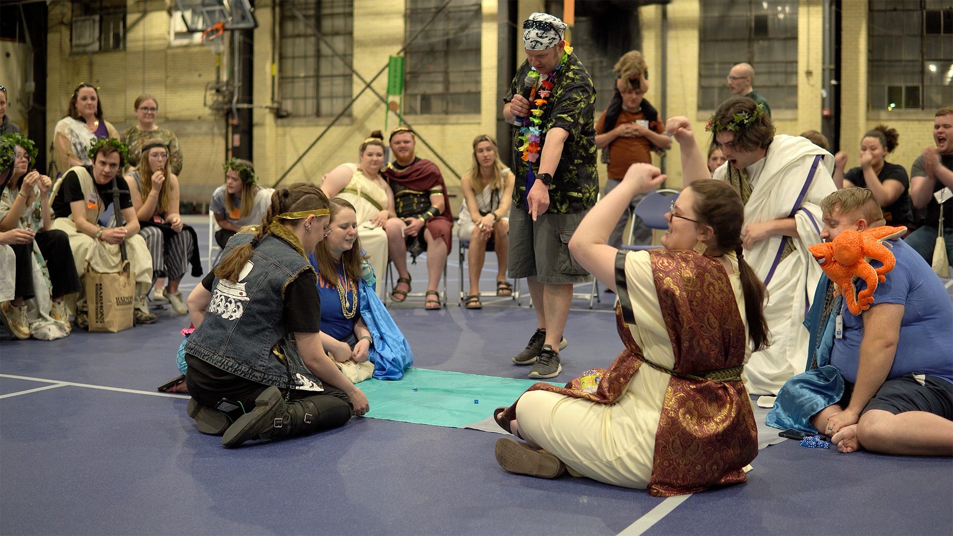 A costumed man points at players rolling dice on a cloth laid out on the floor.
