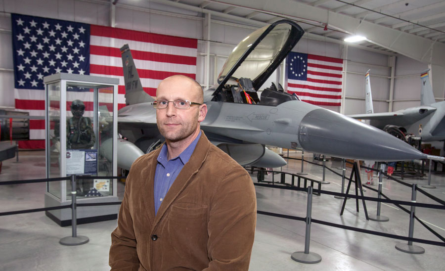 Justin Hall stands in front of an airforce jet with distinguished poise.
