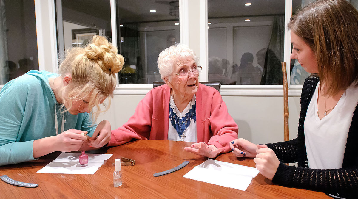 Students perform manicures on a retirement home resident.